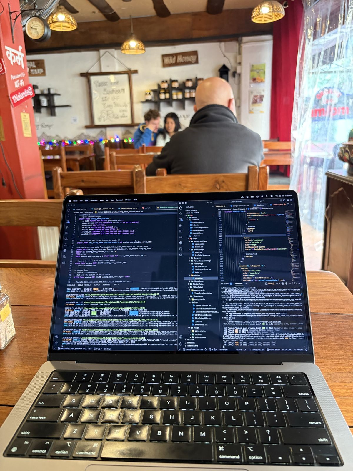 A laptop showing a database migration, in a café with wooden benches and warm pendant lights